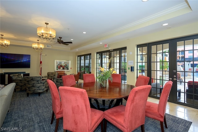 dining space with ornamental molding, a healthy amount of sunlight, light tile floors, and a tray ceiling