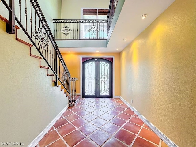 foyer entrance with french doors, a high ceiling, and dark tile floors