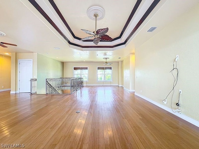 spare room featuring light hardwood / wood-style floors, ceiling fan, crown molding, and a raised ceiling