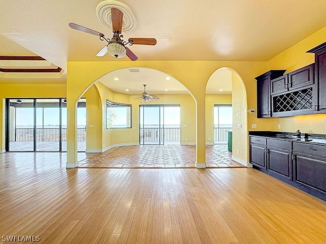 unfurnished living room featuring sink, ceiling fan, and light hardwood / wood-style flooring