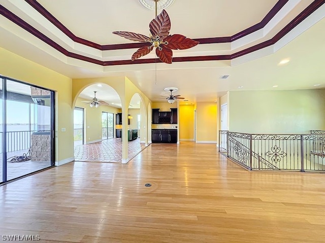 unfurnished living room featuring ceiling fan, a raised ceiling, and light hardwood / wood-style flooring