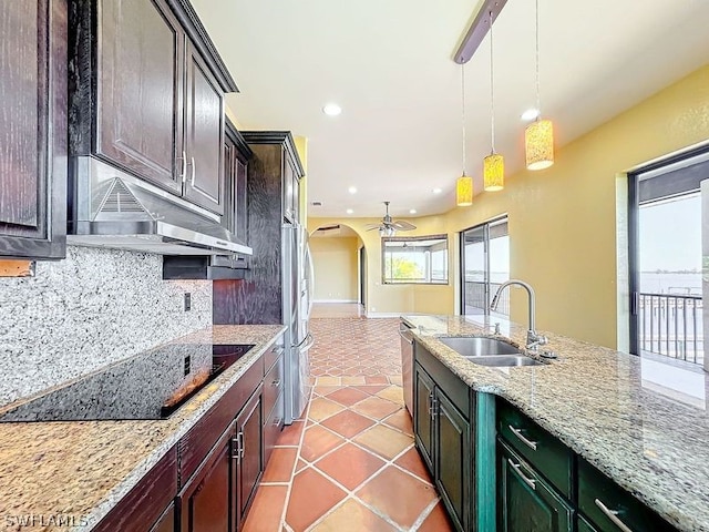 kitchen featuring decorative light fixtures, ceiling fan, light tile flooring, tasteful backsplash, and sink