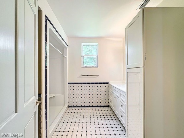 bathroom with tile walls, tile floors, and vanity