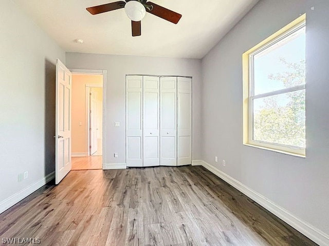 unfurnished bedroom featuring a closet, light hardwood / wood-style flooring, and ceiling fan