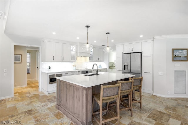 kitchen with white cabinets, backsplash, decorative light fixtures, and a kitchen island with sink