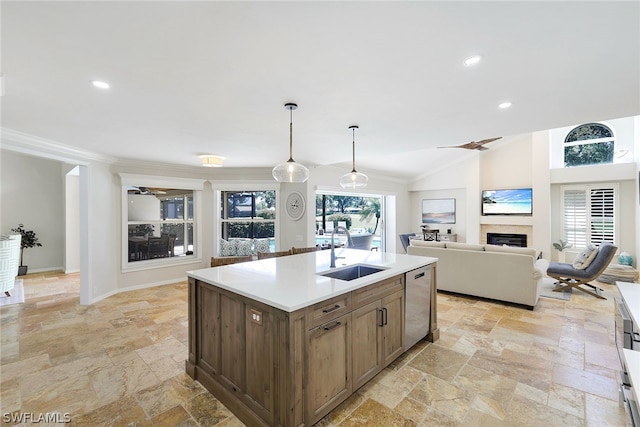 kitchen with pendant lighting, a kitchen island with sink, crown molding, sink, and dishwasher