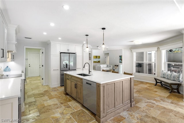 kitchen with decorative light fixtures, a center island with sink, stainless steel appliances, white cabinetry, and sink