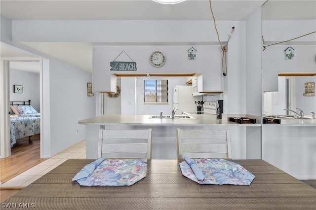 interior space with sink, white cabinetry, light tile floors, and stove