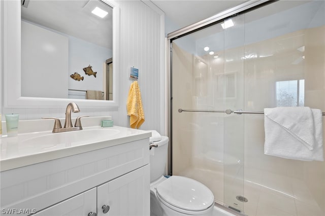 bathroom featuring a shower with door, toilet, and large vanity