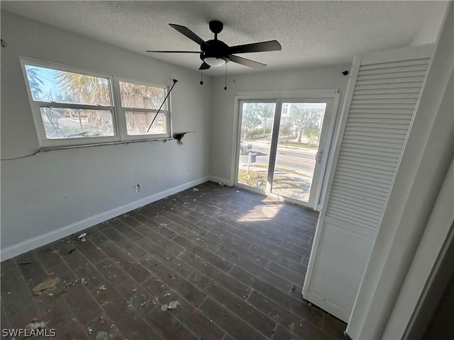 spare room featuring a textured ceiling, plenty of natural light, ceiling fan, and dark wood-type flooring