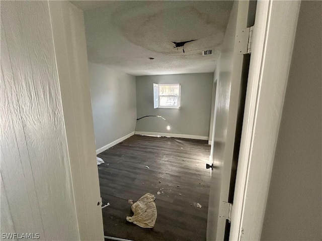 spare room with a textured ceiling and dark hardwood / wood-style flooring