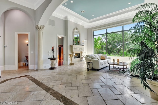 interior space with crown molding, tile floors, a tray ceiling, a towering ceiling, and ornate columns