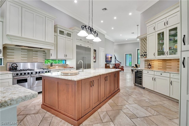 kitchen featuring wine cooler, high quality appliances, tasteful backsplash, hanging light fixtures, and ornamental molding