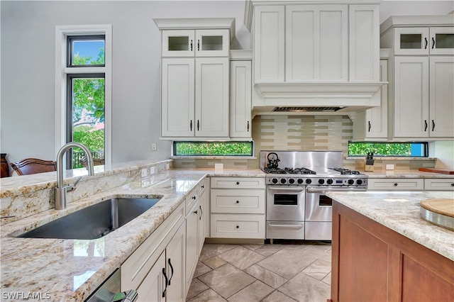 kitchen featuring custom exhaust hood, light tile floors, double oven range, white cabinets, and sink