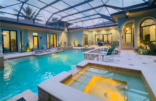 view of swimming pool with a patio, a lanai, an in ground hot tub, and pool water feature