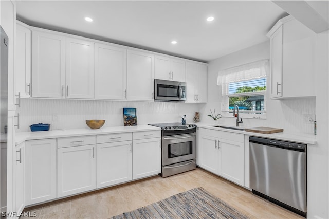 kitchen featuring light hardwood / wood-style flooring, white cabinetry, backsplash, stainless steel appliances, and sink