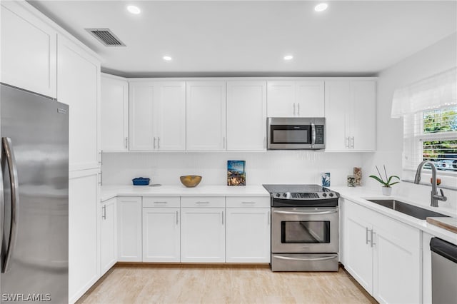 kitchen featuring white cabinets, sink, light wood-type flooring, and stainless steel appliances