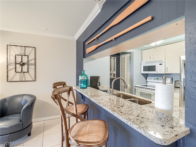 kitchen featuring kitchen peninsula, white appliances, white cabinets, a kitchen breakfast bar, and sink