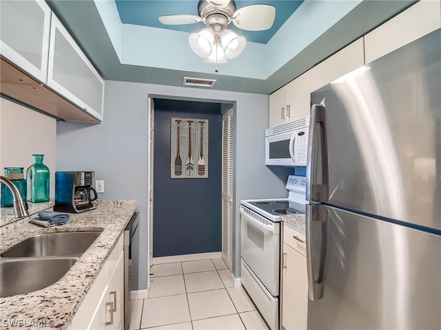 kitchen with appliances with stainless steel finishes, ceiling fan, sink, white cabinetry, and light stone countertops