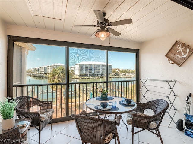 sunroom / solarium featuring a water view and ceiling fan