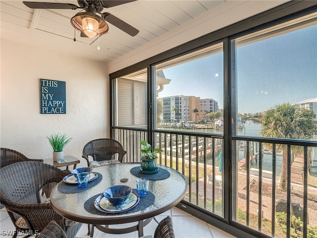 sunroom featuring a water view and ceiling fan