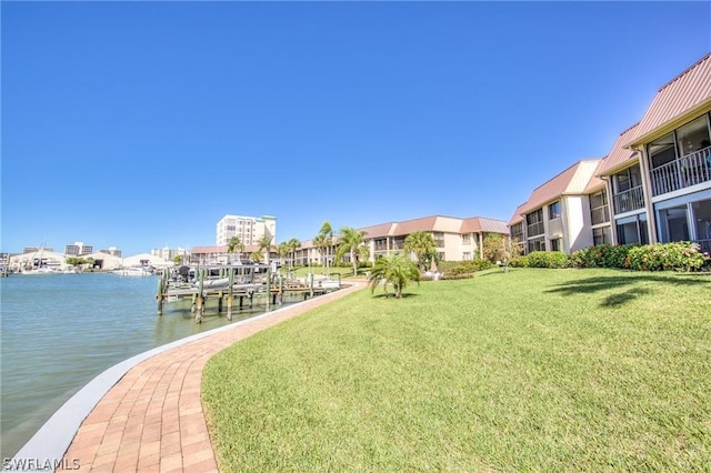 view of home's community with a water view, a dock, and a lawn