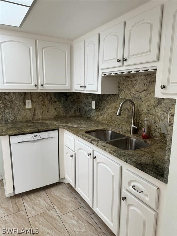 kitchen featuring tasteful backsplash, dark stone counters, sink, white dishwasher, and white cabinetry