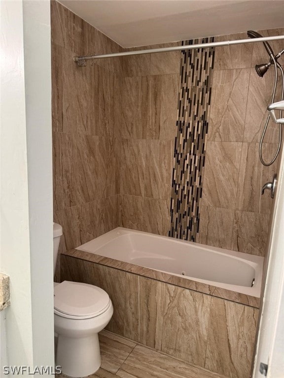 bathroom with tiled shower / bath and toilet