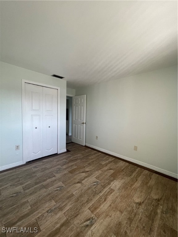 unfurnished bedroom with a closet and dark hardwood / wood-style flooring