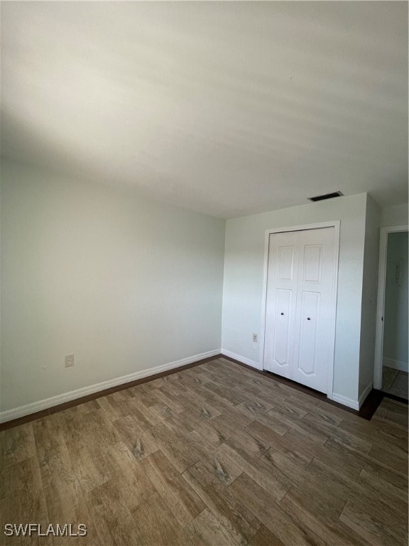 unfurnished bedroom featuring a closet and dark hardwood / wood-style floors