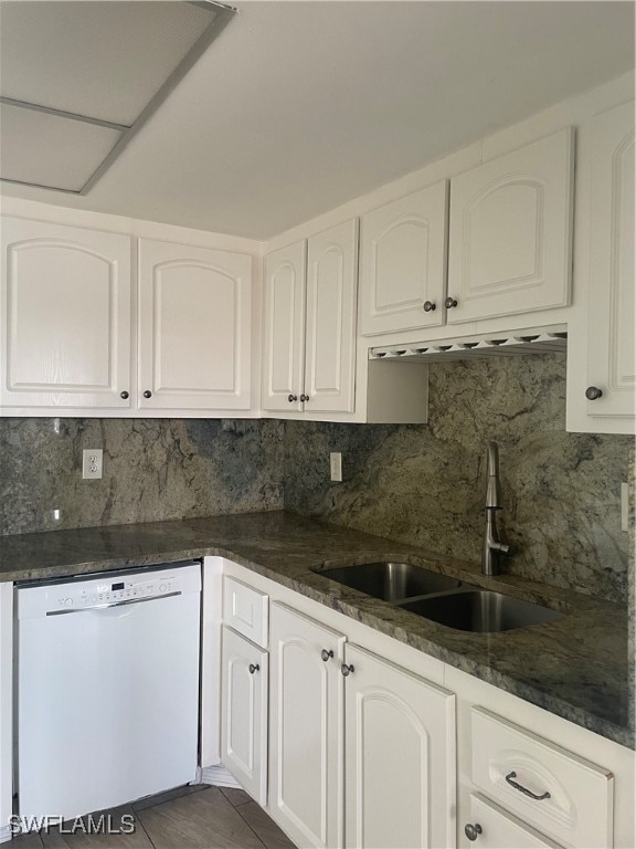 kitchen featuring decorative backsplash, white cabinets, sink, dark stone counters, and dishwasher