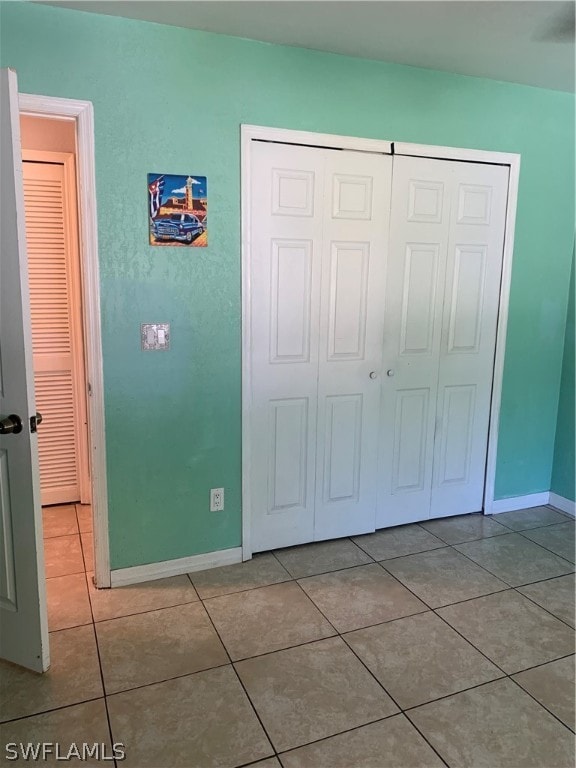 unfurnished bedroom featuring tile flooring and a closet