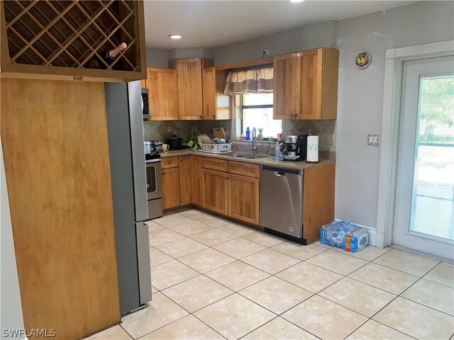 kitchen with sink, tasteful backsplash, light tile floors, and stainless steel appliances