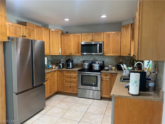 kitchen with light stone counters, light tile floors, backsplash, and appliances with stainless steel finishes