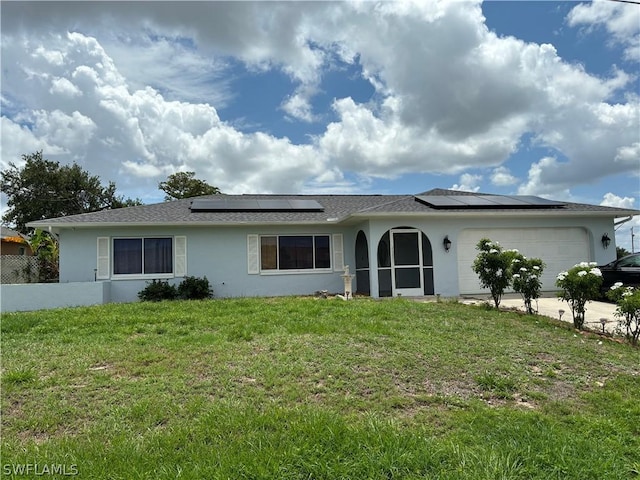 single story home featuring an attached garage, driveway, roof mounted solar panels, a front lawn, and stucco siding