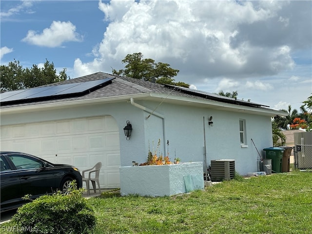 view of home's exterior featuring central AC, a garage, solar panels, and a lawn