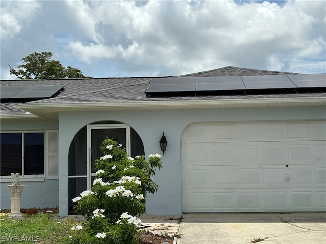 exterior space with a garage and solar panels