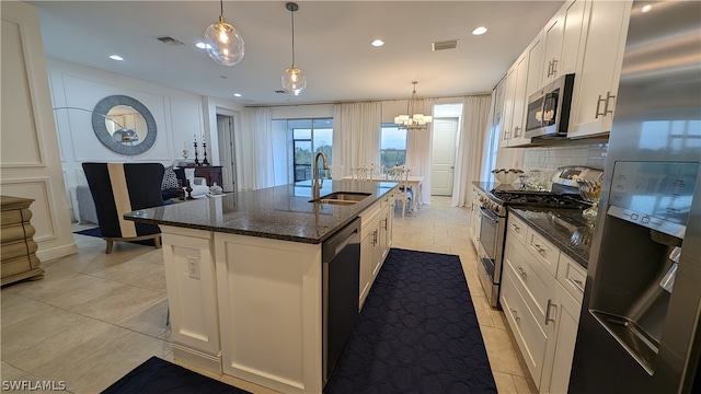 kitchen with sink, an island with sink, white cabinets, appliances with stainless steel finishes, and decorative light fixtures