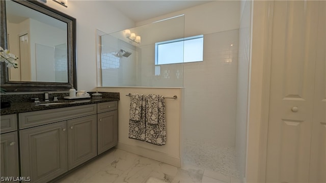 bathroom with a tile shower and vanity