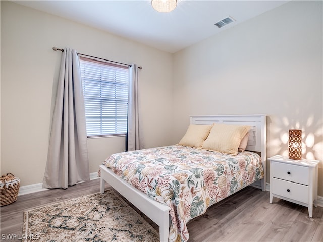 bedroom with light wood-style flooring, visible vents, and baseboards