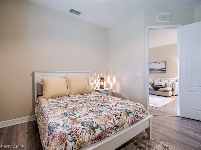 bedroom featuring visible vents, baseboards, and wood finished floors