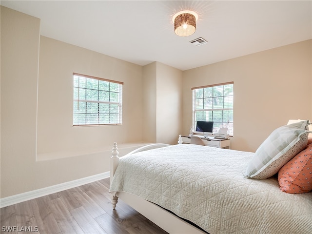 bedroom featuring visible vents, baseboards, and wood finished floors