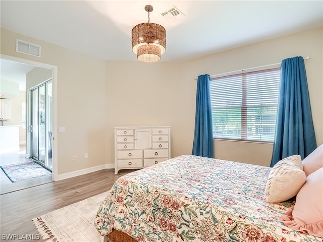 bedroom with wood finished floors, visible vents, and baseboards