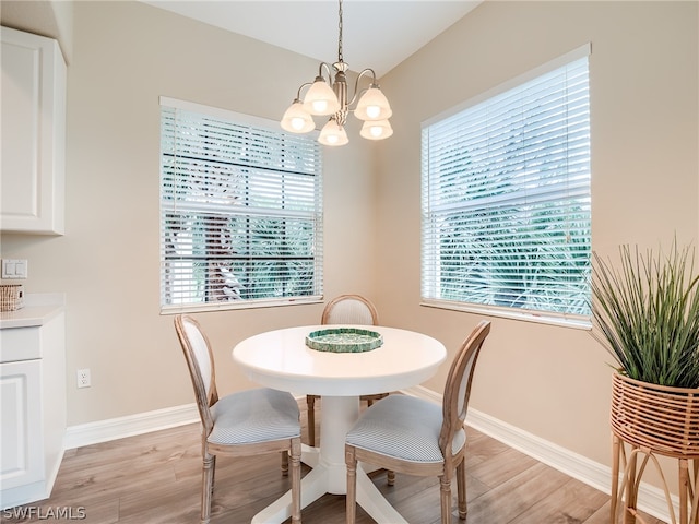 dining space with a chandelier, baseboards, and light wood finished floors