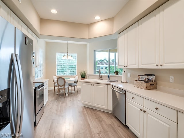 kitchen featuring a notable chandelier, light wood finished floors, stainless steel appliances, light countertops, and white cabinetry