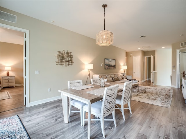 dining space with light wood-type flooring and a notable chandelier