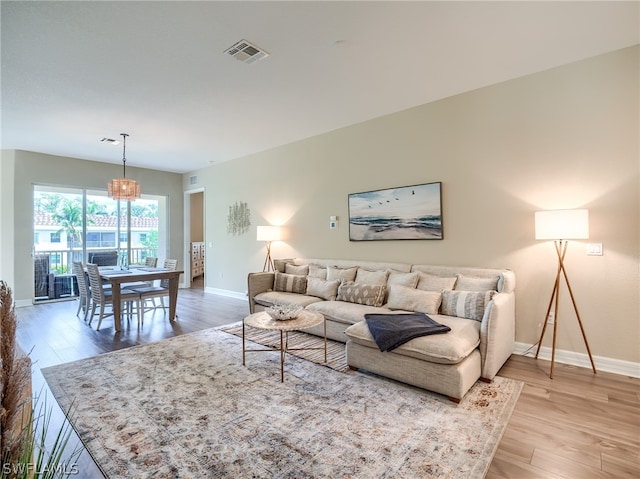 living room featuring light wood-type flooring and a chandelier