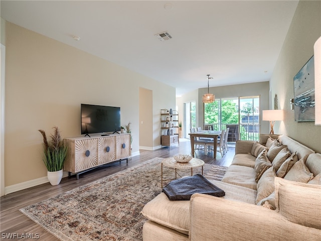 living area with baseboards, visible vents, and wood finished floors