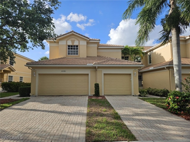 view of front of property featuring a garage, a tiled roof, decorative driveway, and stucco siding