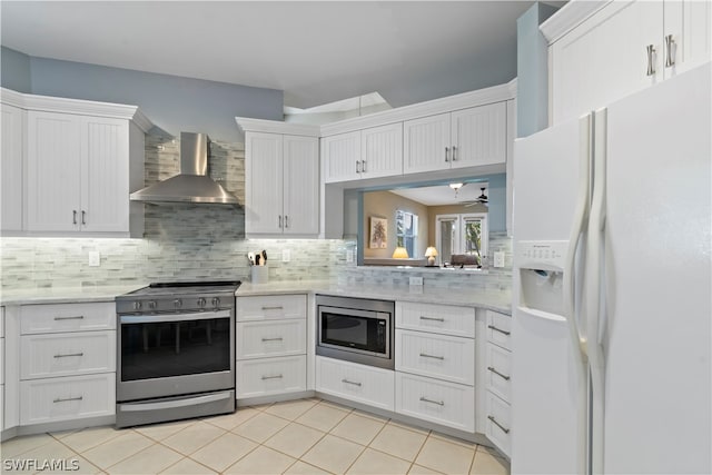 kitchen featuring white cabinets, appliances with stainless steel finishes, wall chimney range hood, and tasteful backsplash